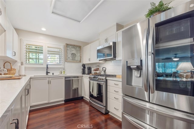 kitchen with backsplash, light countertops, appliances with stainless steel finishes, dark wood-style floors, and a sink