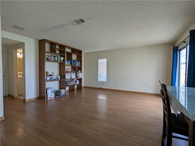 living area with visible vents, baseboards, a textured ceiling, and dark wood-style flooring