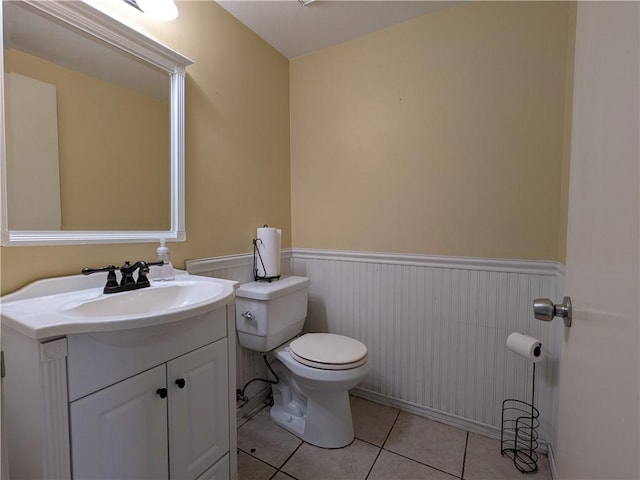 bathroom featuring tile patterned flooring, toilet, vanity, and a wainscoted wall