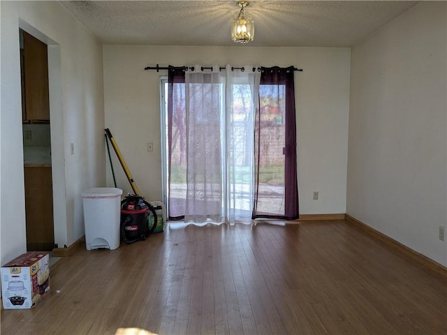 empty room featuring baseboards, a textured ceiling, and hardwood / wood-style floors