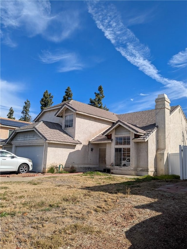 view of front of property featuring fence, an attached garage, a chimney, stucco siding, and a tiled roof