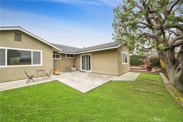 back of property featuring stucco siding, a lawn, roof with shingles, and a patio area