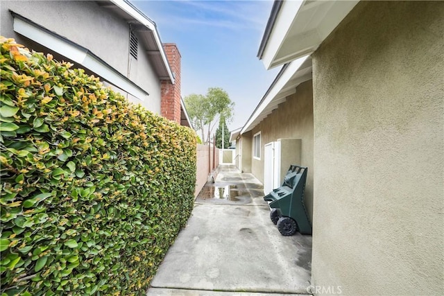 view of home's exterior with stucco siding, a patio area, and fence