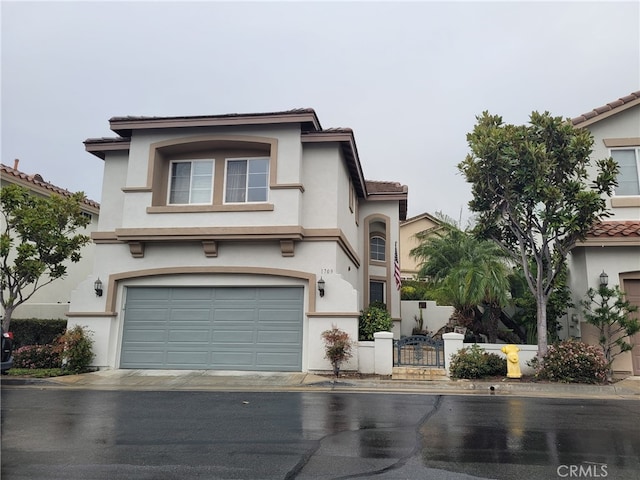 mediterranean / spanish-style home featuring a tiled roof, stucco siding, and an attached garage