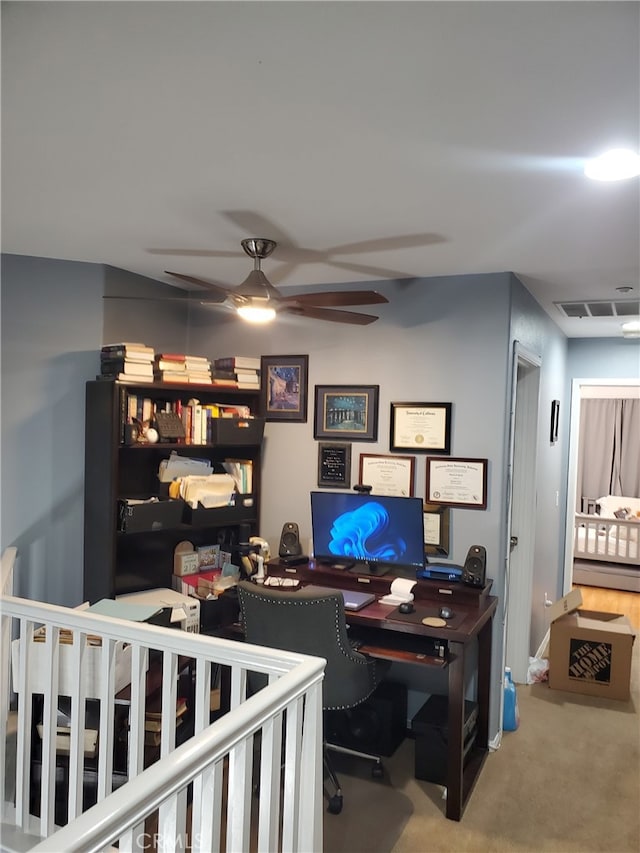 carpeted office space featuring visible vents and a ceiling fan