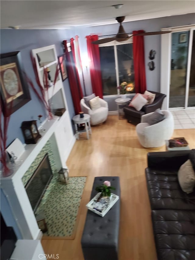 living room featuring a fireplace, a ceiling fan, and wood finished floors