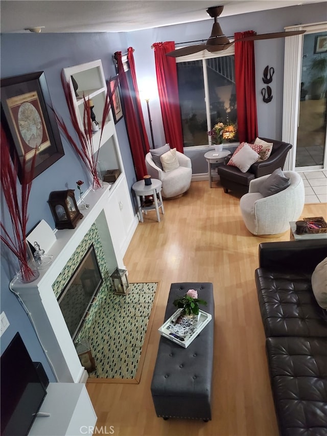 living area featuring ceiling fan, wood finished floors, and a fireplace