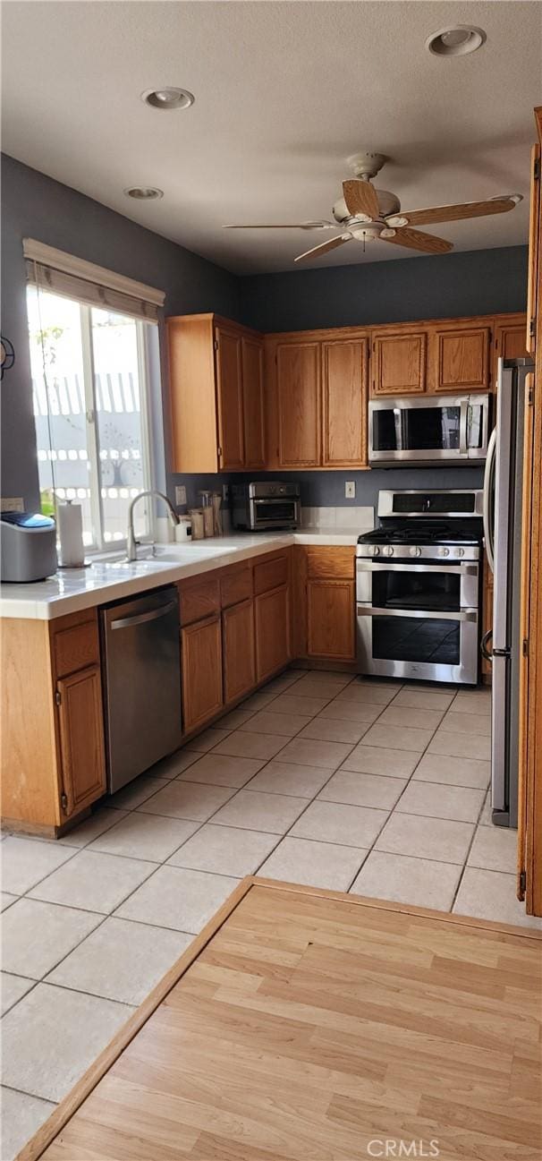 kitchen featuring light countertops, light tile patterned floors, a ceiling fan, and appliances with stainless steel finishes