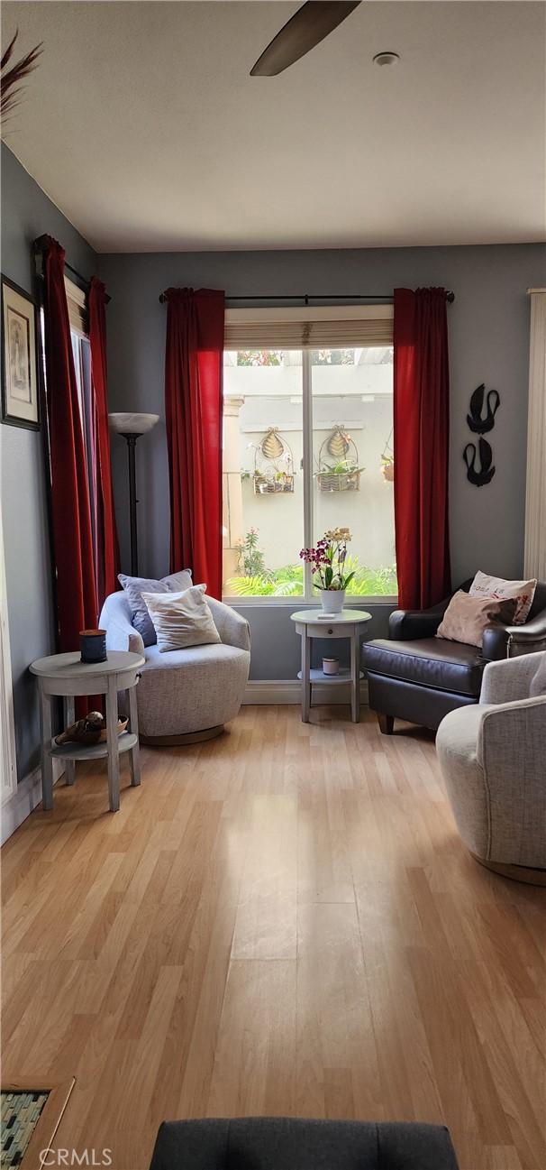 living area featuring light wood-style flooring and a ceiling fan