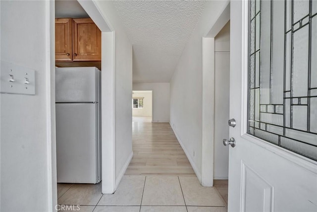 interior space with light tile patterned floors, baseboards, and a textured ceiling