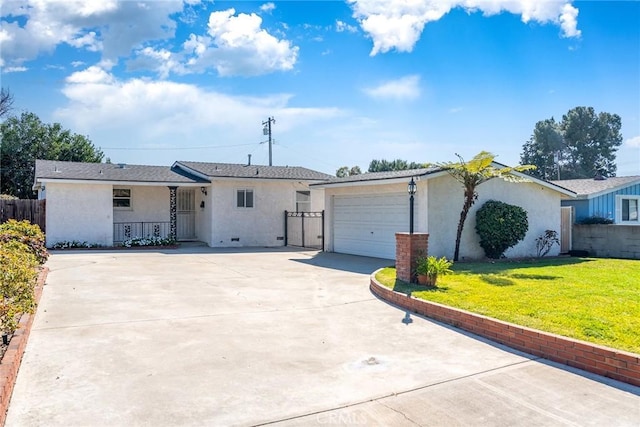 view of front of house with a front lawn, fence, stucco siding, a garage, and driveway