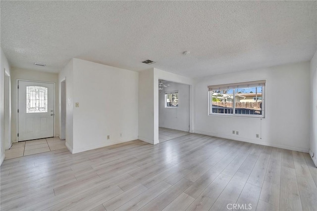 unfurnished living room with light wood-style floors, visible vents, and baseboards