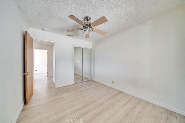 unfurnished bedroom featuring visible vents, a closet, light wood finished floors, and a textured ceiling