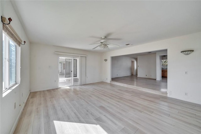 empty room featuring baseboards, light wood-style floors, visible vents, and ceiling fan