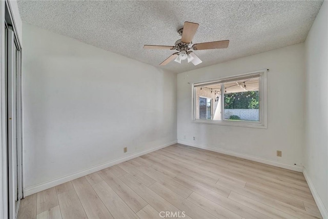 empty room with baseboards, a textured ceiling, ceiling fan, and light wood finished floors