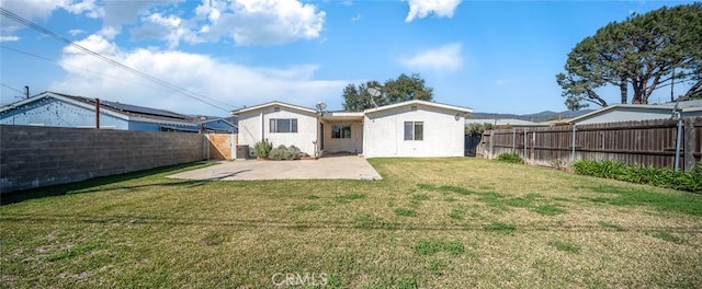 rear view of property with a yard, a fenced backyard, stucco siding, and a patio area