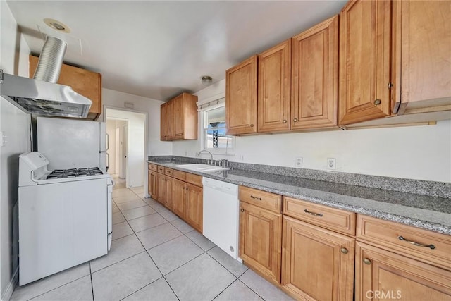 kitchen featuring brown cabinets, a sink, dark stone counters, white appliances, and light tile patterned floors