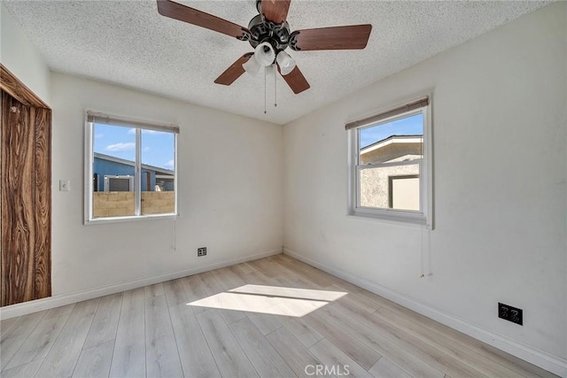 empty room featuring plenty of natural light, wood finished floors, and a textured ceiling