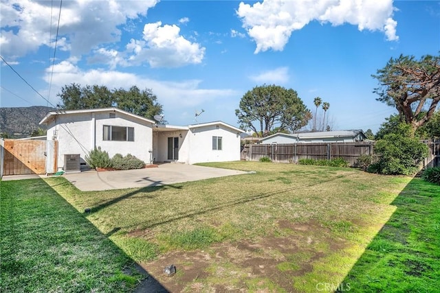 rear view of property featuring a yard, a patio, and fence