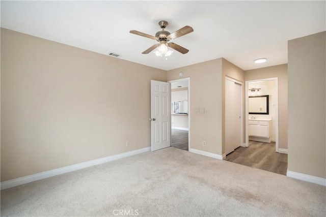 unfurnished bedroom featuring visible vents, a ceiling fan, ensuite bath, carpet, and baseboards