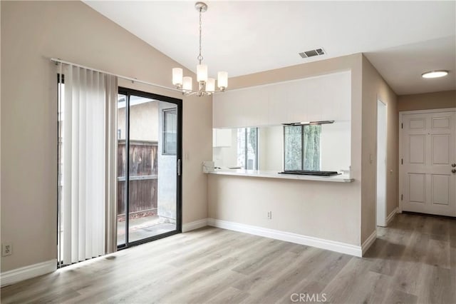 empty room featuring light wood finished floors, visible vents, baseboards, lofted ceiling, and an inviting chandelier