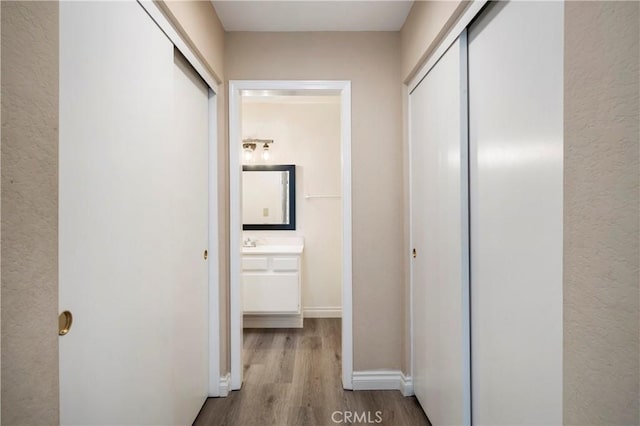 corridor with baseboards and wood finished floors