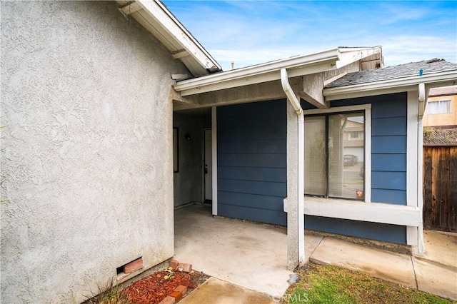 entrance to property featuring stucco siding and fence