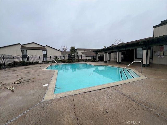 community pool with a patio area and fence