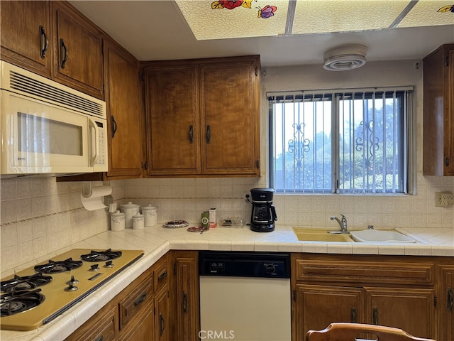 kitchen with a sink, white appliances, and backsplash