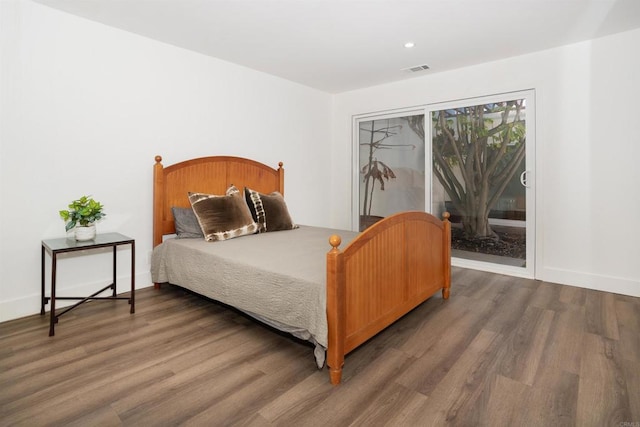 bedroom featuring access to outside, wood finished floors, visible vents, and baseboards