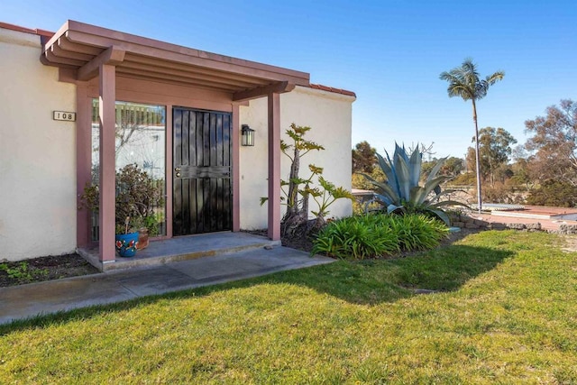 entrance to property with a yard and stucco siding