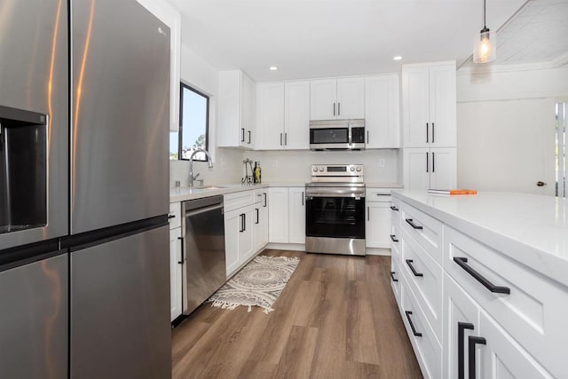 kitchen with stainless steel appliances, white cabinetry, dark wood-style floors, and light countertops