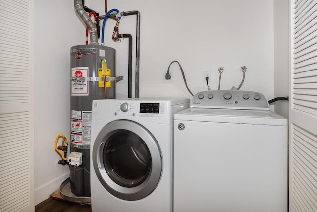 clothes washing area featuring washer and dryer, gas water heater, wood finished floors, and baseboards