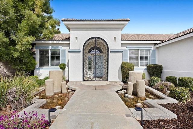 entrance to property with stucco siding and a tile roof