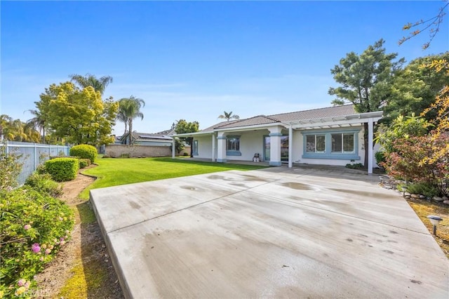 rear view of property featuring stucco siding, a lawn, a tile roof, fence, and concrete driveway