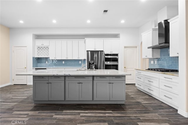 kitchen with a spacious island, gray cabinetry, appliances with stainless steel finishes, white cabinetry, and wall chimney range hood