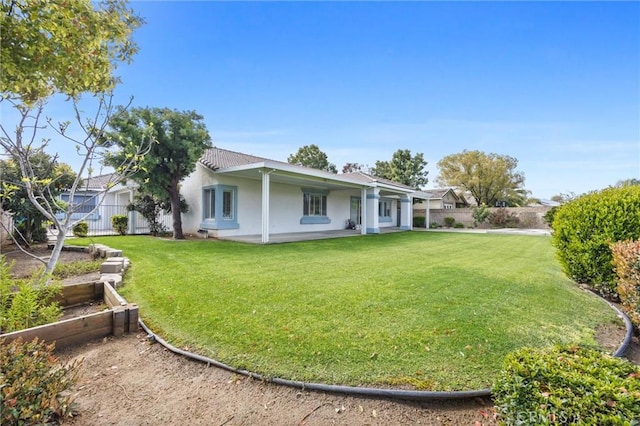 exterior space featuring a garden, stucco siding, a front yard, and fence