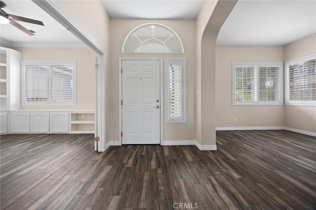 entrance foyer featuring baseboards, arched walkways, a ceiling fan, and dark wood-style flooring