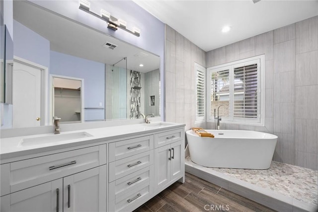 bathroom with a sink, visible vents, tile walls, and double vanity