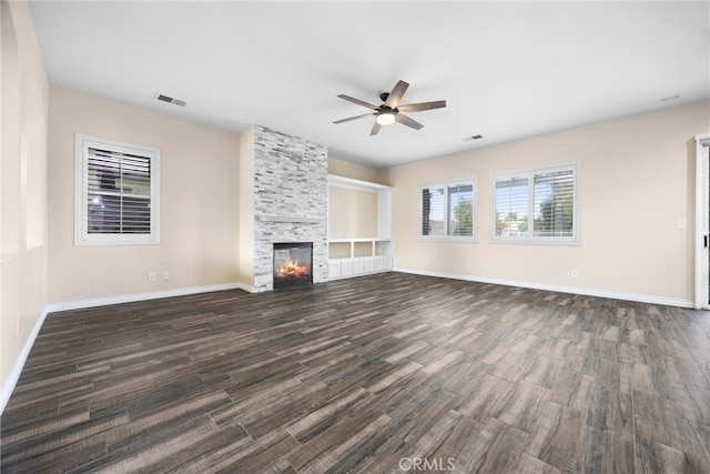 unfurnished living room with visible vents, a large fireplace, baseboards, a ceiling fan, and dark wood-style flooring