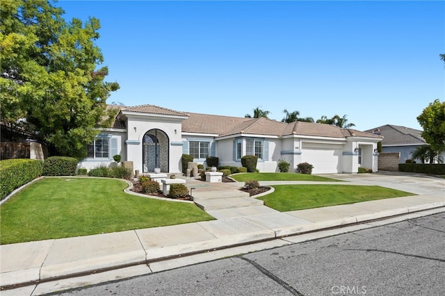 mediterranean / spanish-style home with a tile roof, a front lawn, driveway, and stucco siding