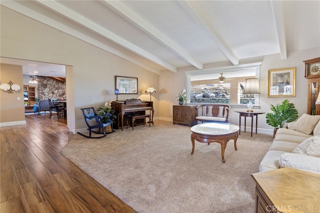 living area with lofted ceiling with beams, baseboards, wood finished floors, and a ceiling fan