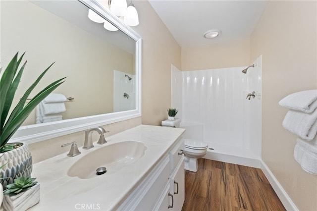 full bathroom featuring baseboards, toilet, wood finished floors, vanity, and a shower