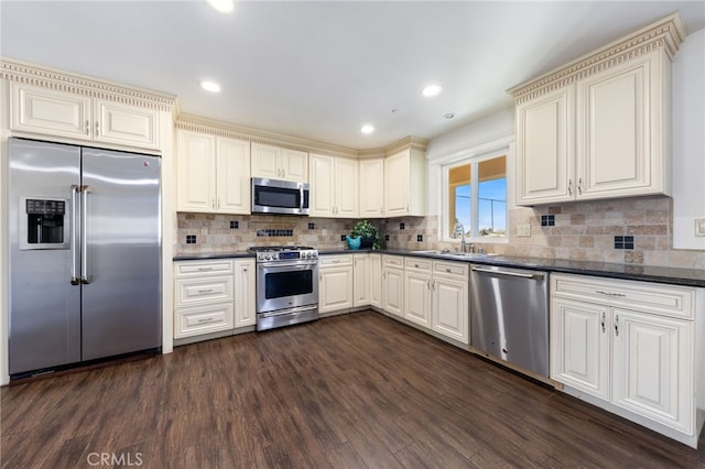 kitchen featuring a sink, stainless steel appliances, tasteful backsplash, and dark wood-style floors