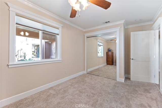 unfurnished bedroom with visible vents, baseboards, ornamental molding, carpet flooring, and a closet