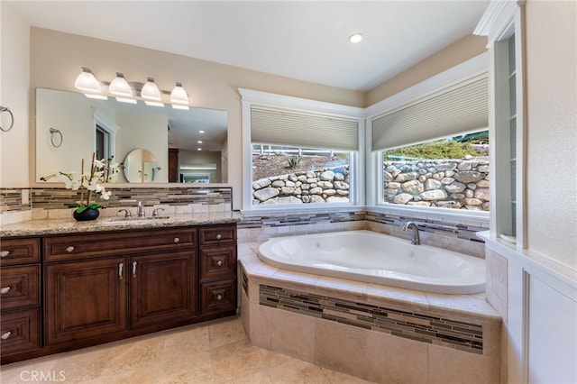 full bath with decorative backsplash, vanity, and a garden tub