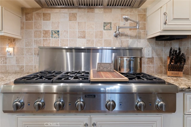 kitchen featuring white cabinets, light stone counters, and backsplash