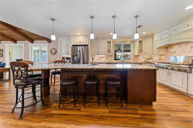 kitchen with stainless steel appliances, glass insert cabinets, light wood-style flooring, and decorative backsplash