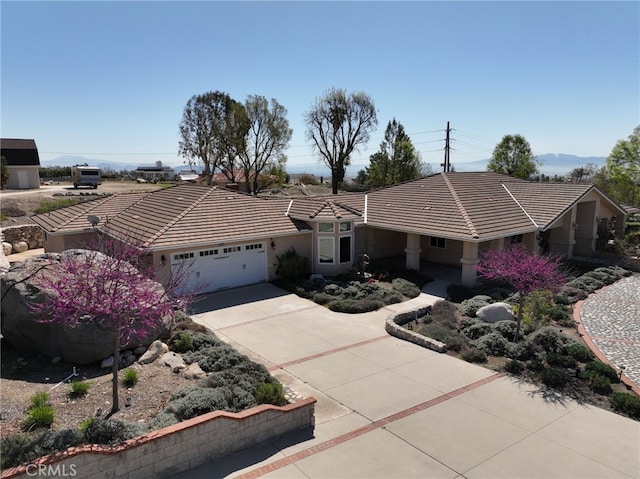 view of front facade with stucco siding, a tiled roof, an attached garage, and concrete driveway