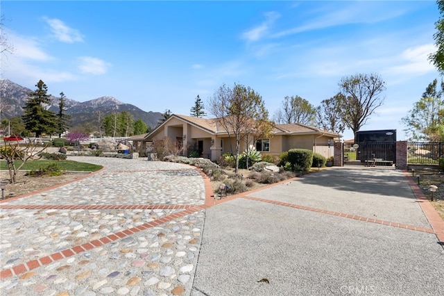 view of front of property featuring stucco siding, a mountain view, driveway, and a gate